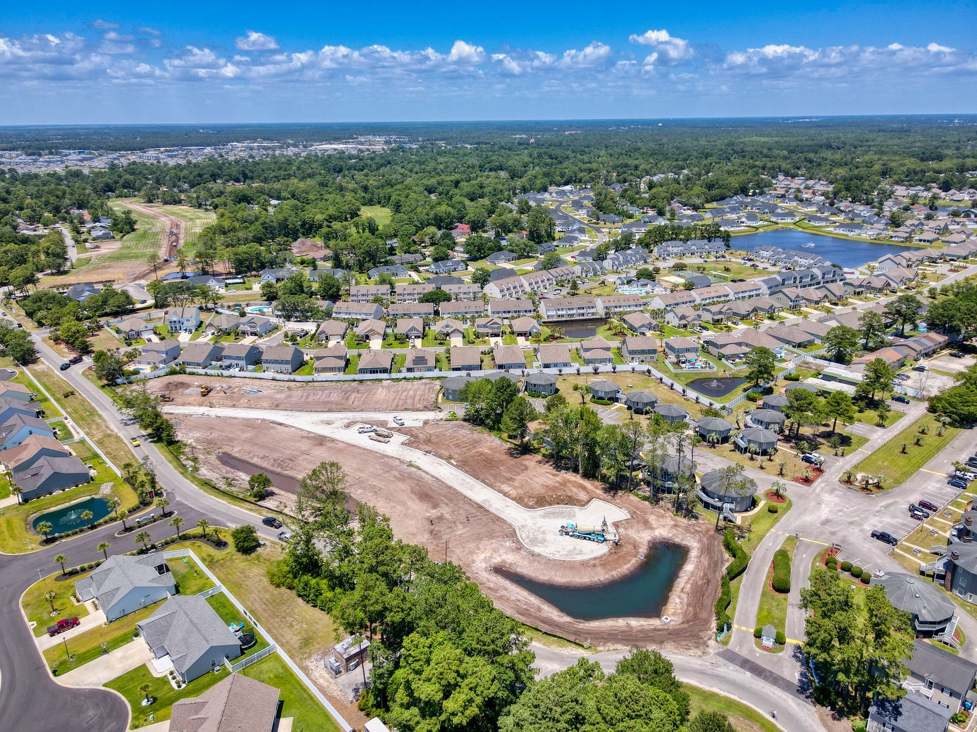 Aerial view of residential area with new construction site and a retention pond.
