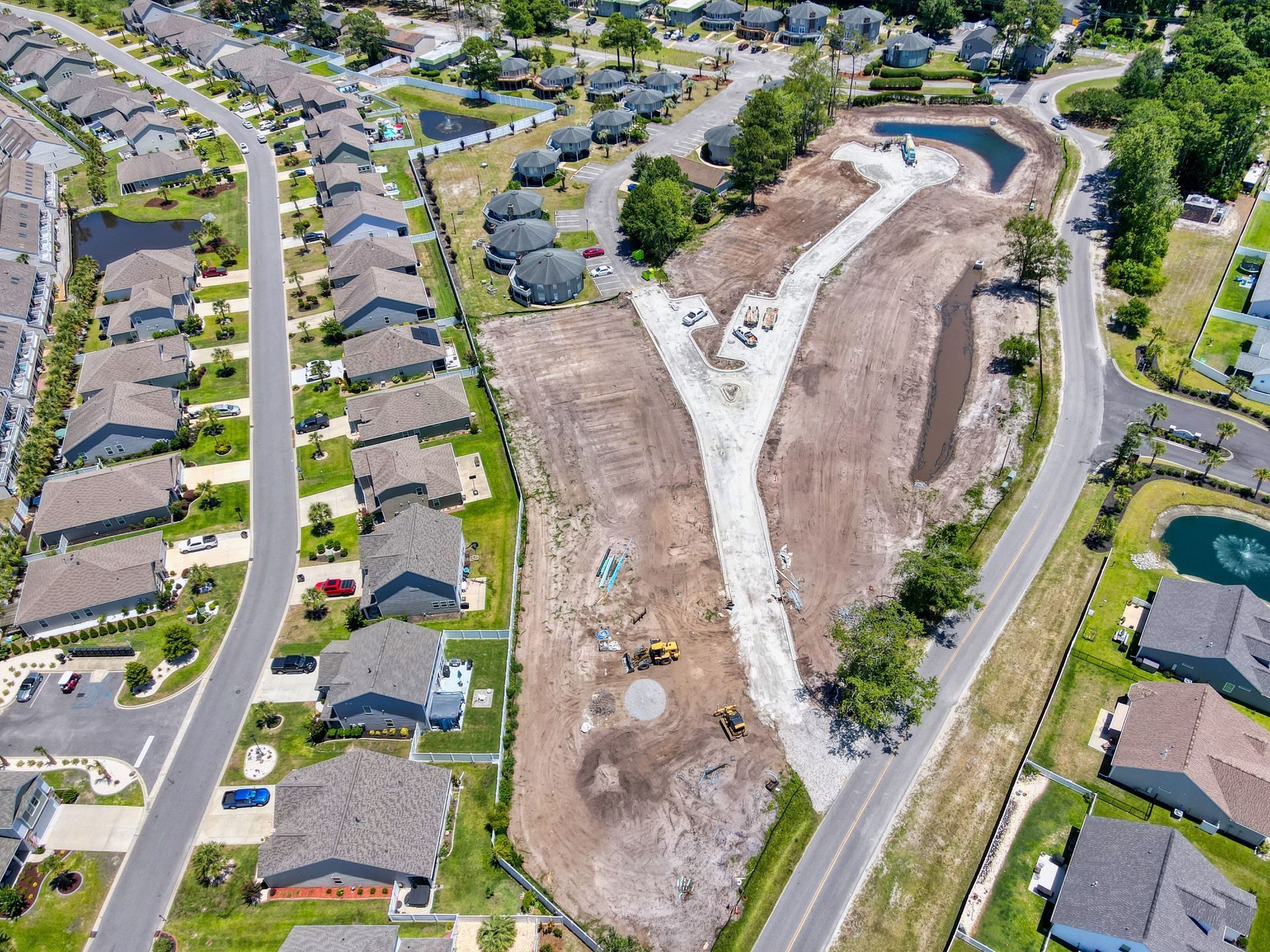 Aerial view of residential construction site and nearby houses.