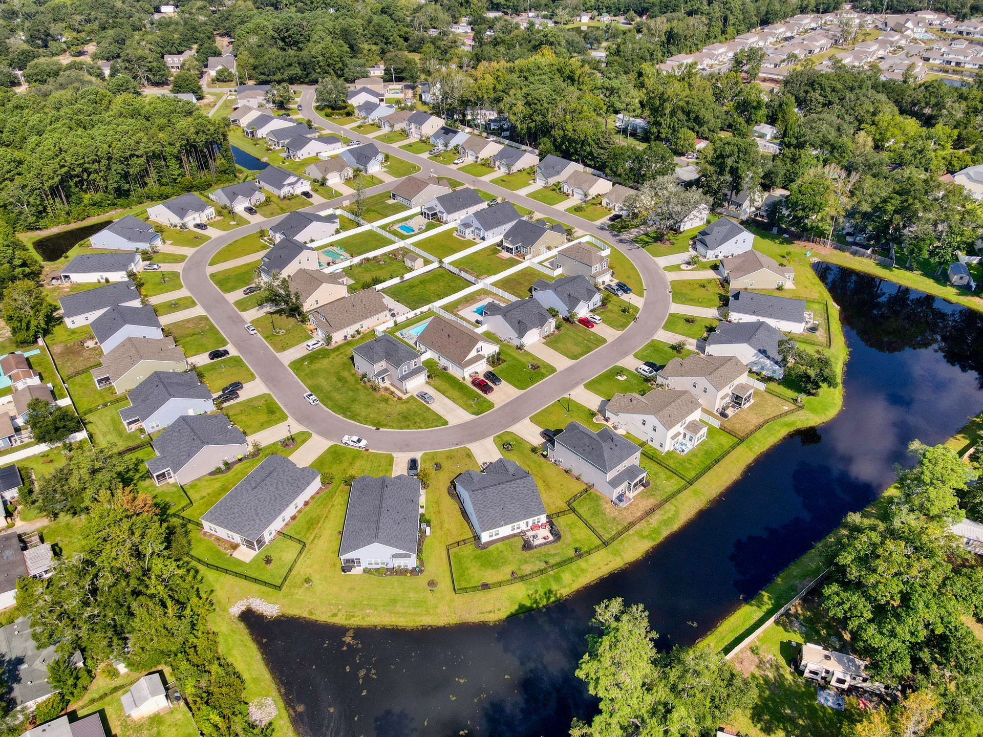Aerial view of a suburban neighborhood with houses surrounding a cul-de-sac and bordering a pond.