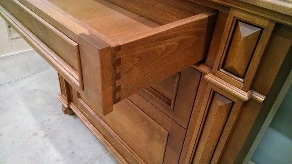 Wooden cabinet drawer pulled open in a room with light tile flooring.