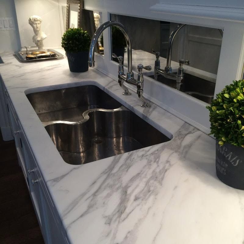 Modern kitchen sink with marble countertop, chrome faucet, and small potted plants