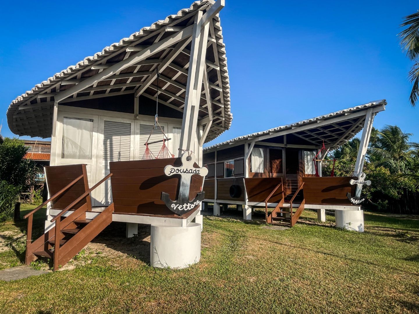 Duas cabines brancas com decks marrons e um quintal gramado sob um céu azul.