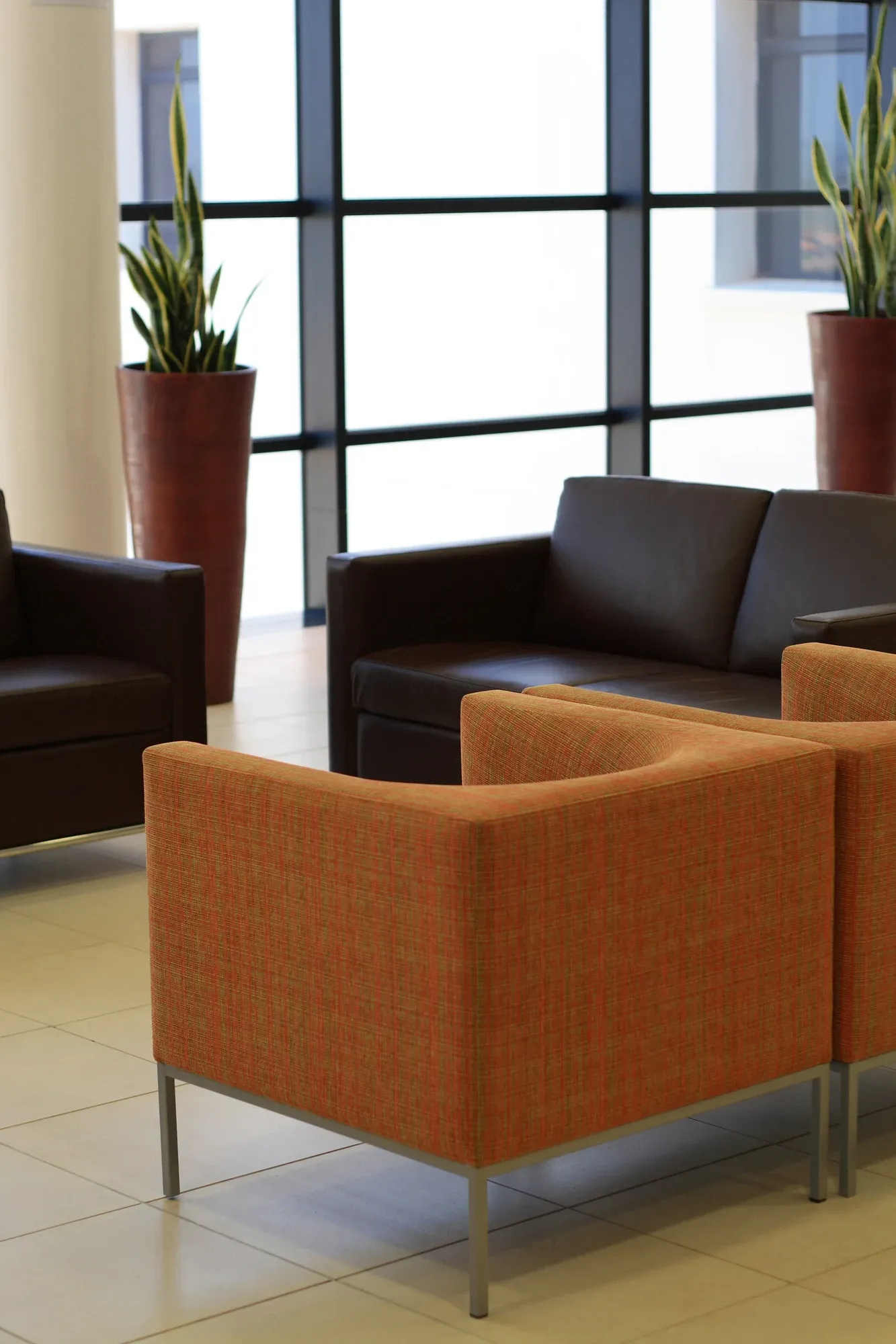 Orange and brown seating area with large windows and potted plants.