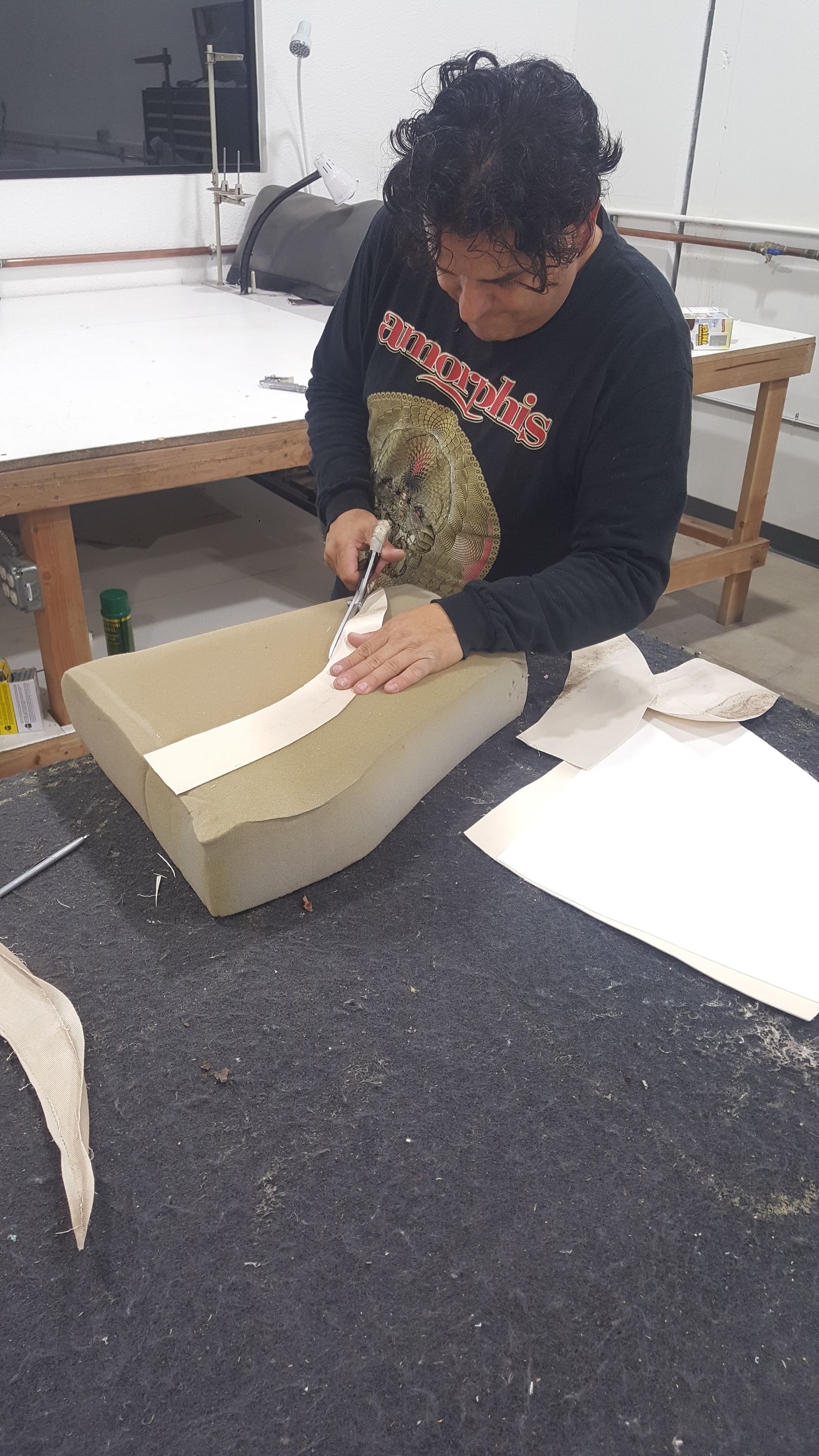 A man is sitting at a table cutting a piece of paper.