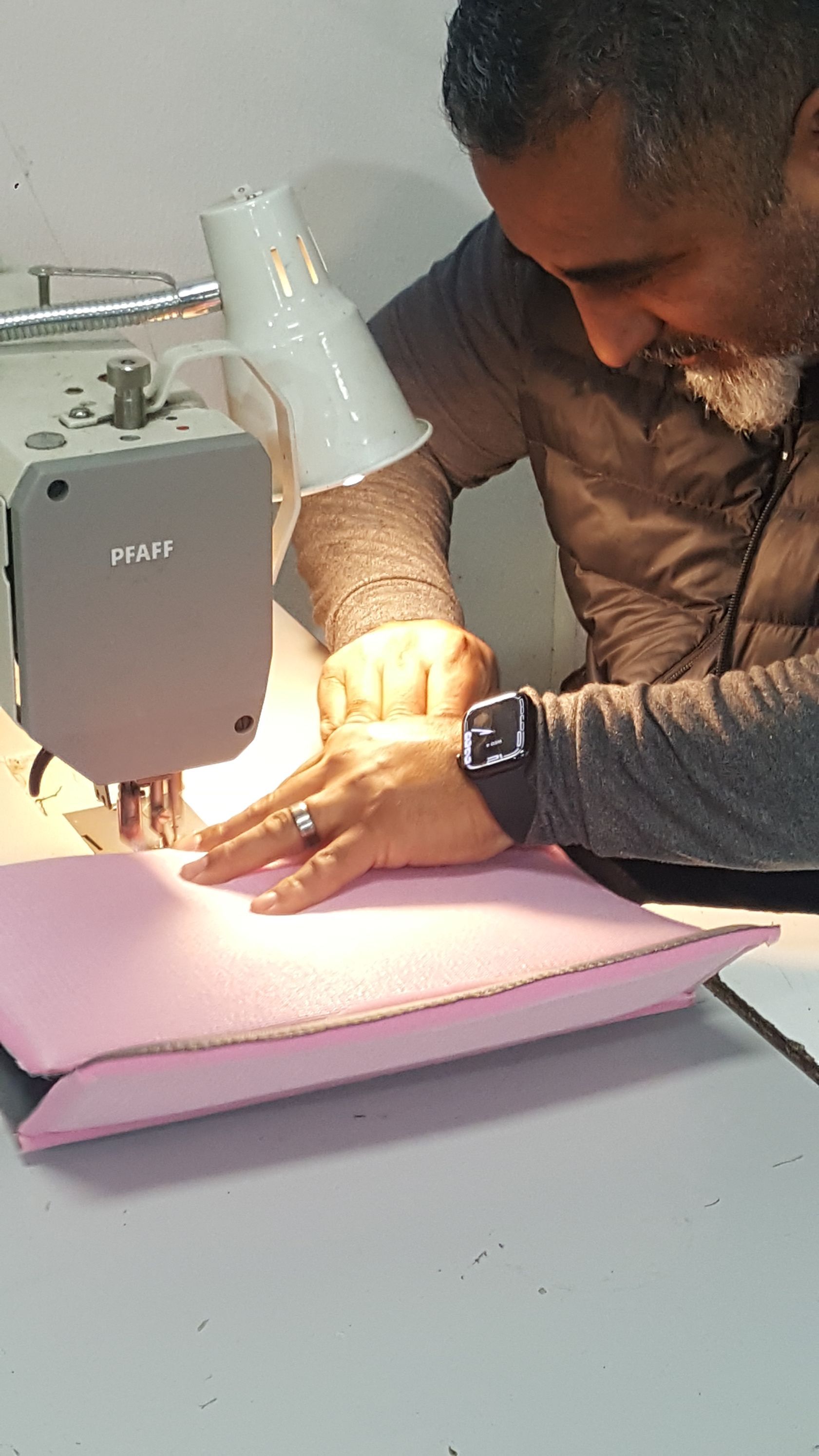 A man is sitting at a table using a sewing machine.