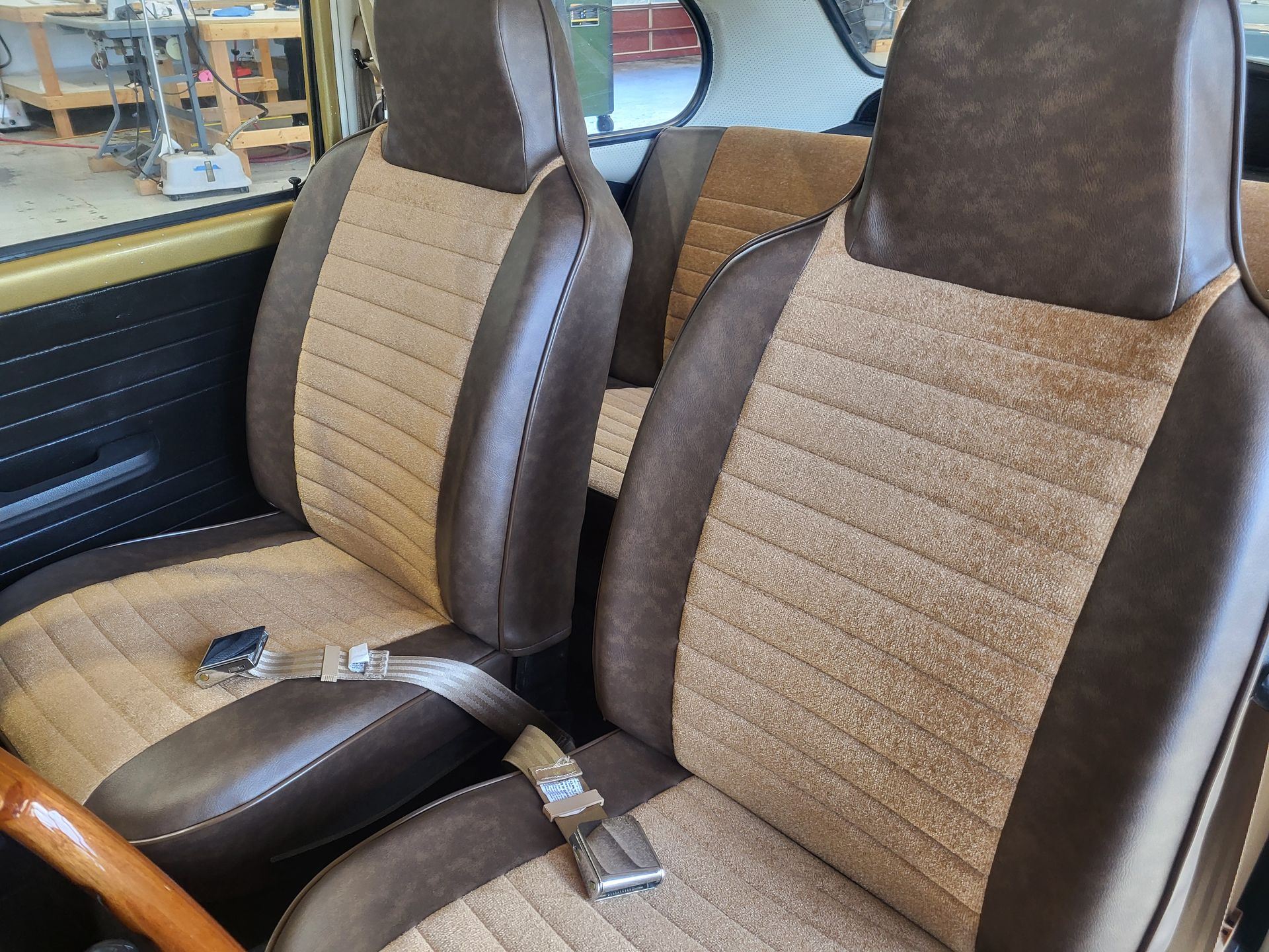 The interior of a car with brown seats and a wooden steering wheel