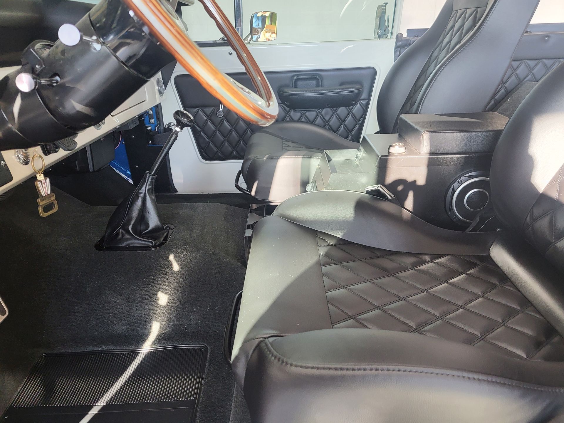 The interior of a car with black leather seats and a wooden steering wheel.