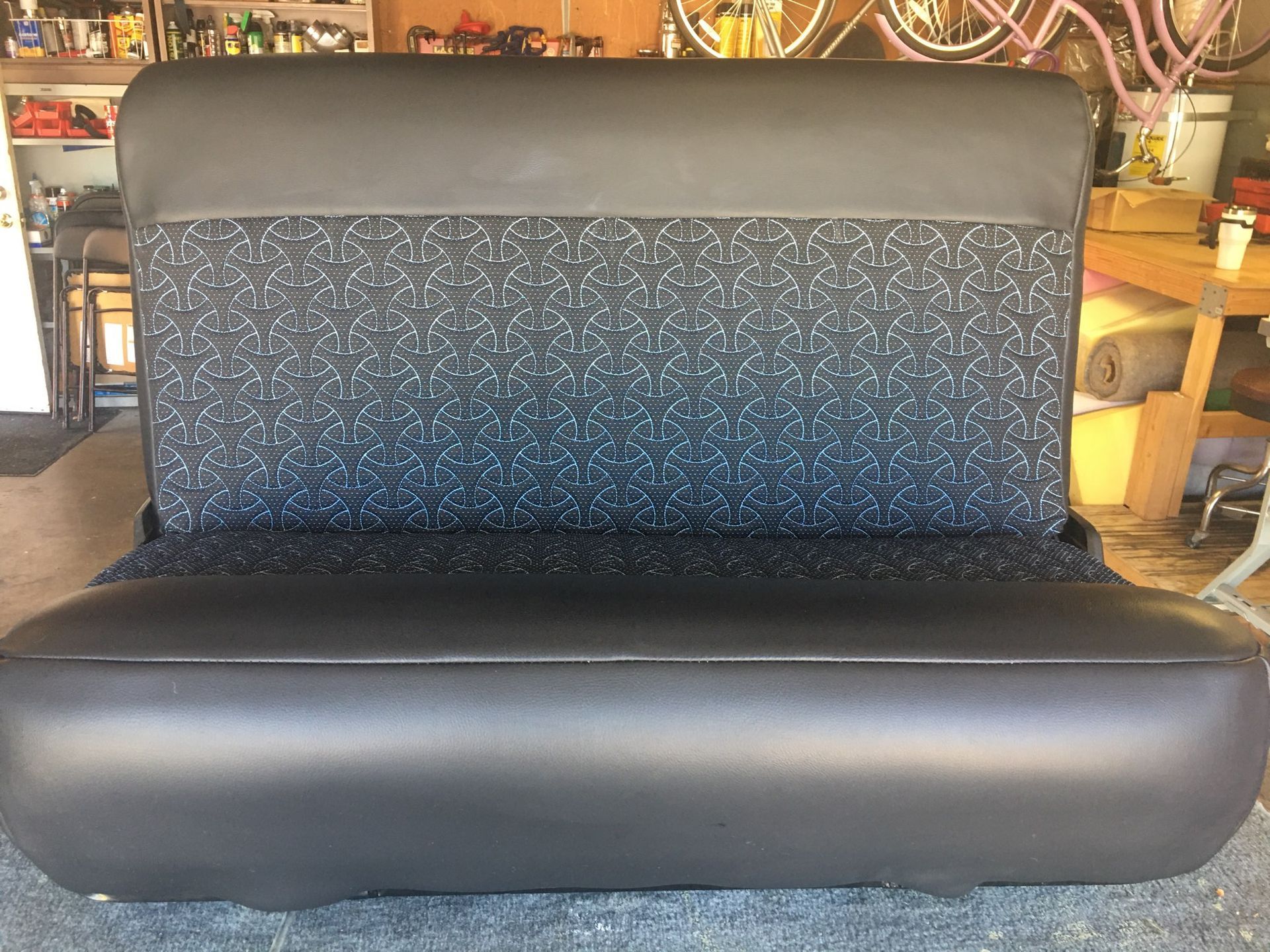 A black couch is sitting on a carpet in a garage.