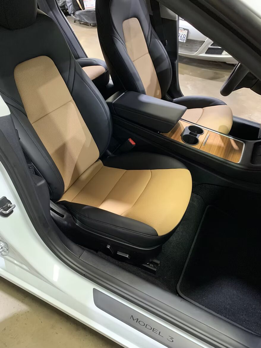 The interior of a tesla model 3 with tan and black seats.