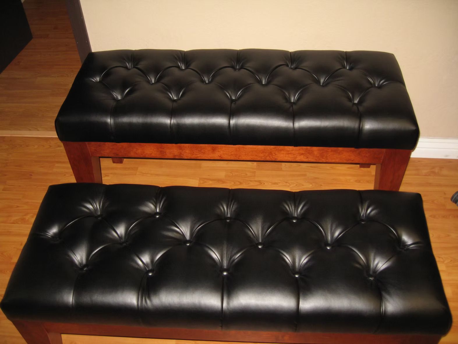 Two black leather benches are sitting on a wooden floor