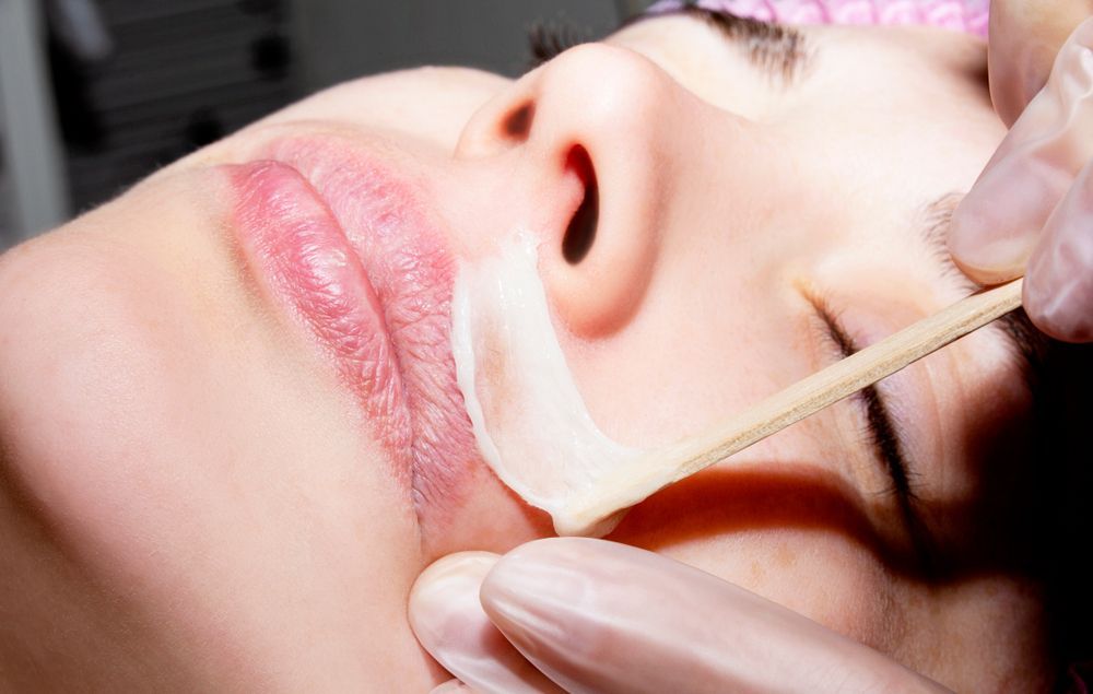 Person having facial hair removed with wax. Technician applies wax strip to upper lip. Admire Skincare and Beauty in Taree, NSW