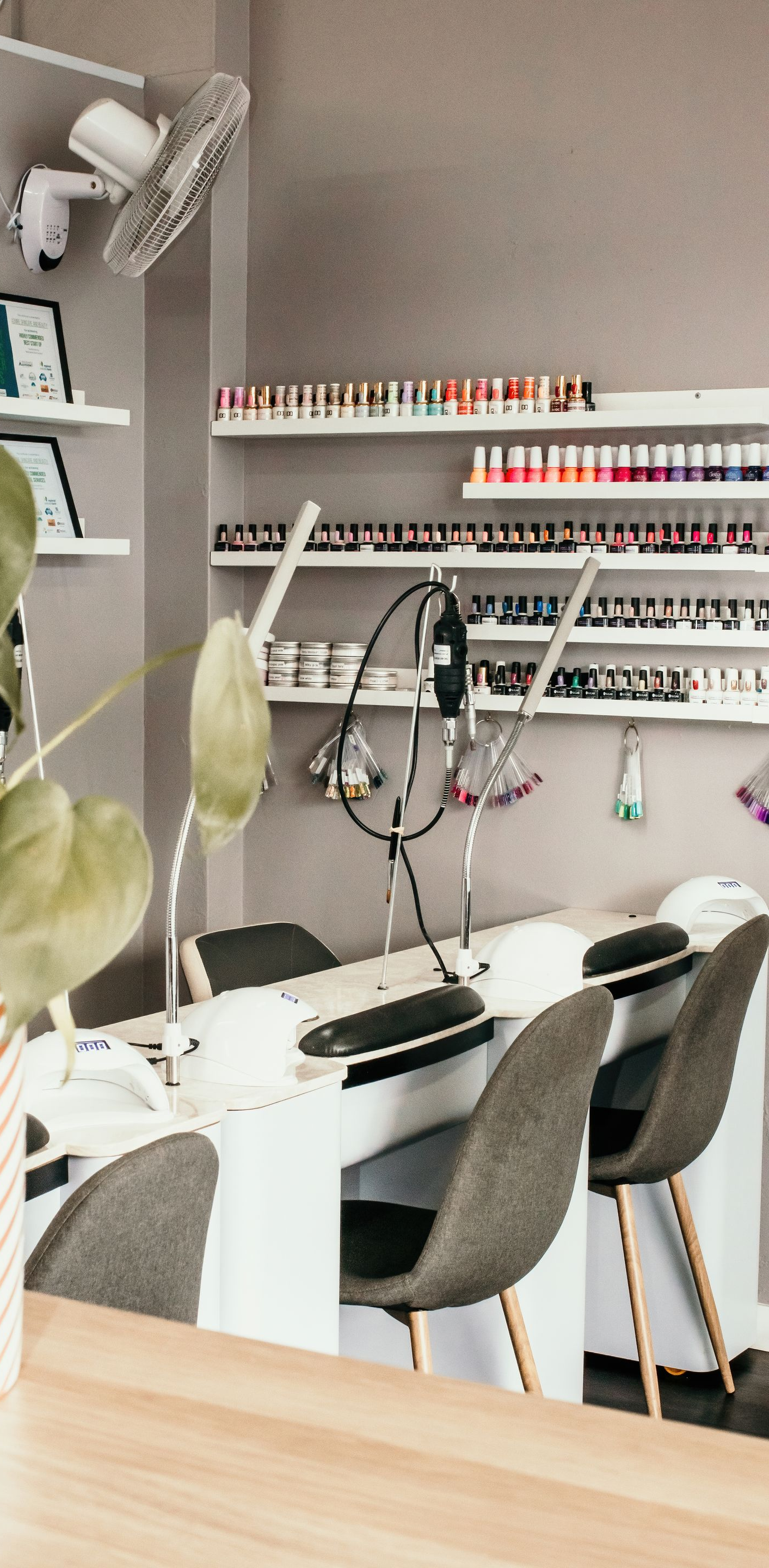 Nail salon interior with manicure stations, shelves of nail polish, and coloured walls — Admire Skincare and Beauty in Taree, NSW