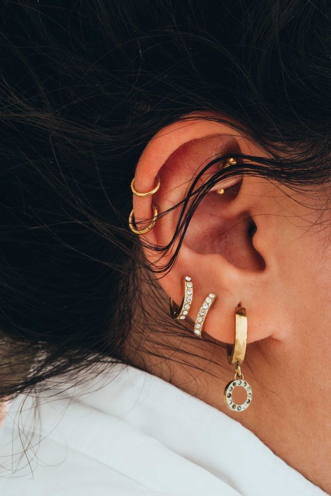 Close-up of ear with multiple gold earrings — Admire Skincare and Beauty in Taree, NSW