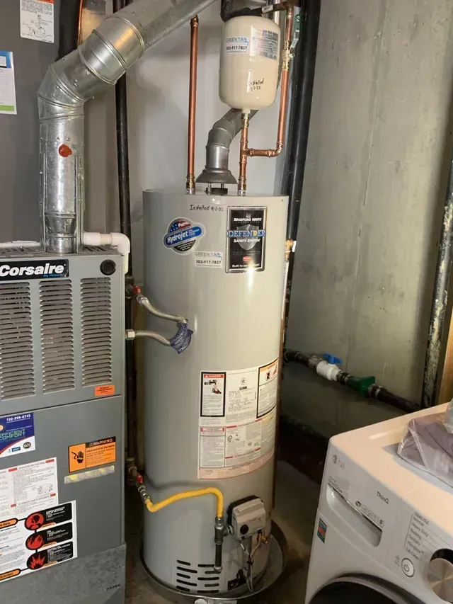 Water heater and furnace in a basement setting. The water heater is next to the furnace and washing machine.