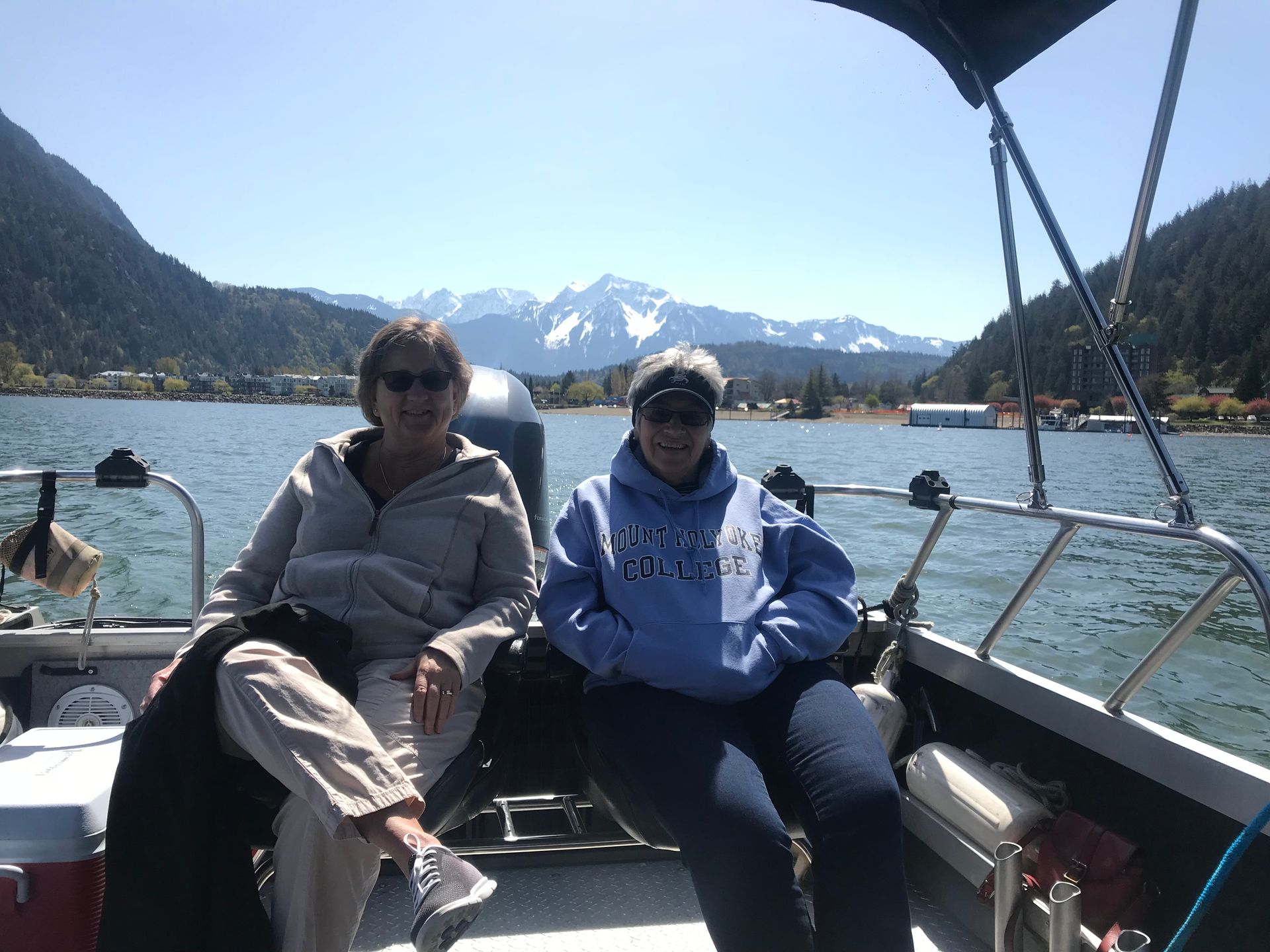 Two people sitting on a boat with mountains and a lake in the background