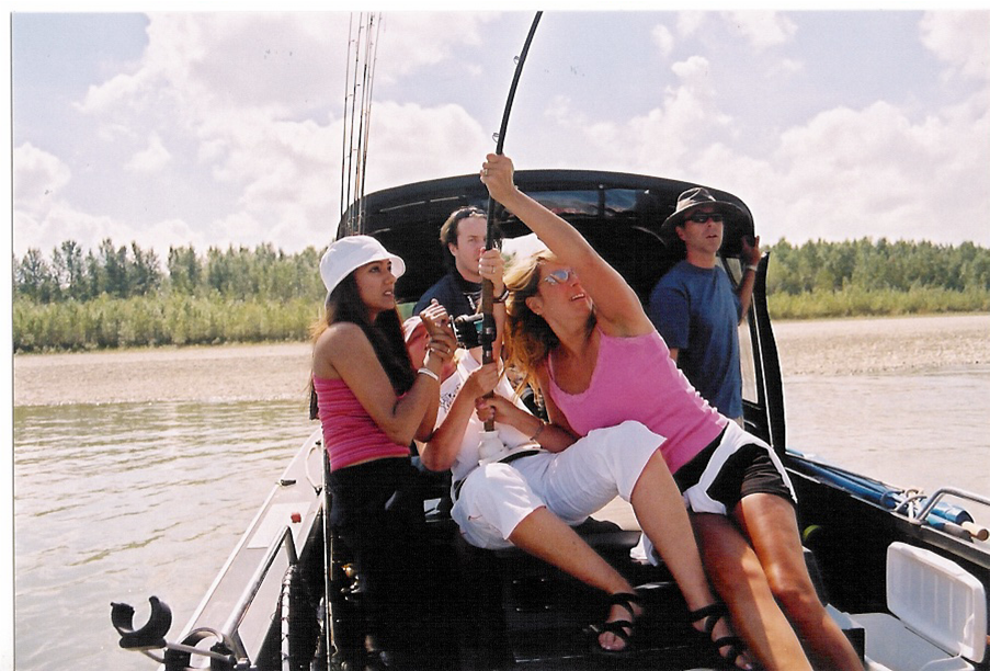 Friends posing on a boat on a lake, smiling and raising drinks in the sun