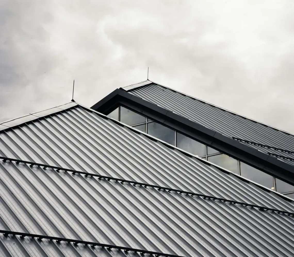 Gray metal roof with ridges under a cloudy sky