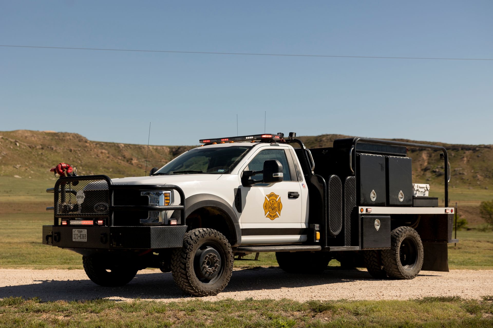 A white truck is parked on the side of a dirt road.