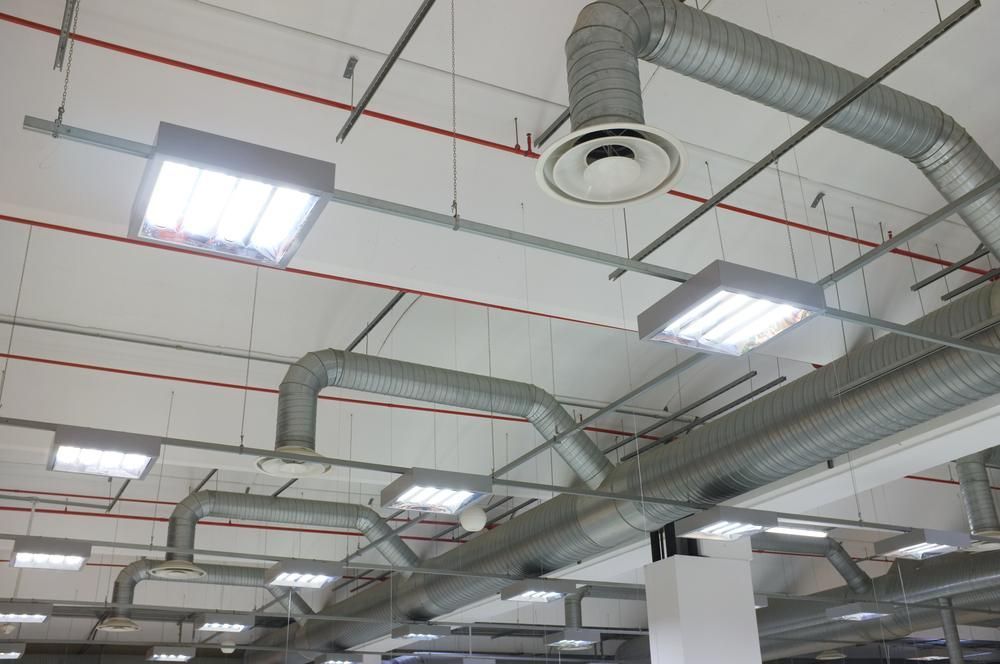 A ceiling with a lot of pipes and lights hanging from it