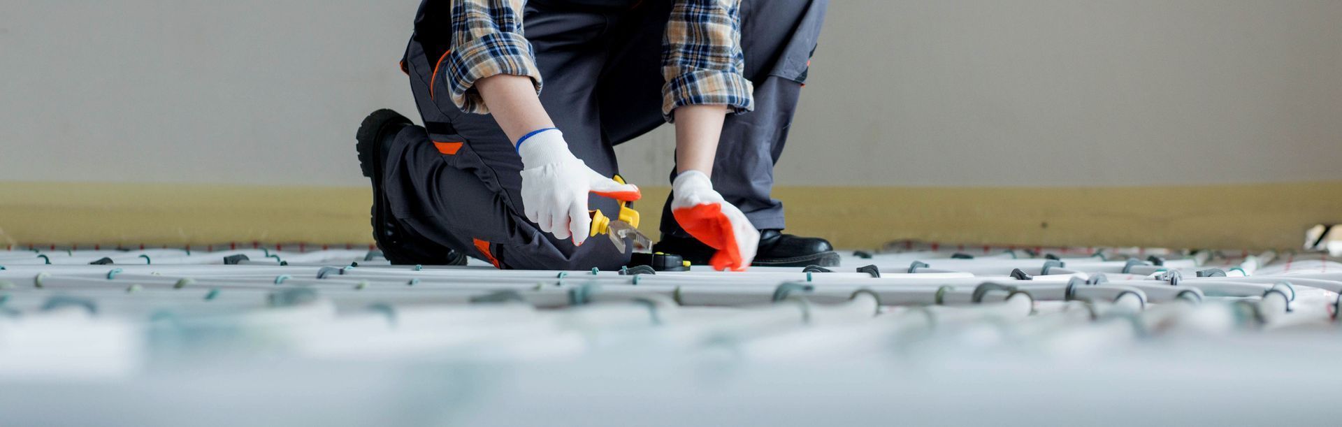 A man is kneeling down on the floor using a measuring tape.