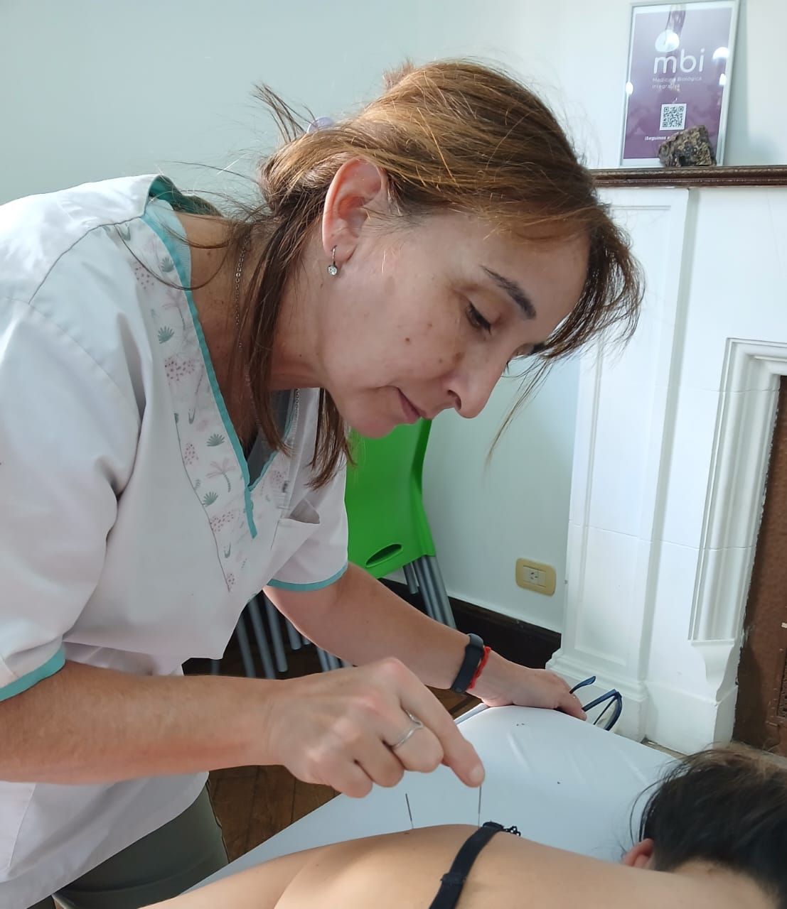 Un dentista con bata blanca examina la boca de un paciente con un instrumento dental en una clínica luminosa.