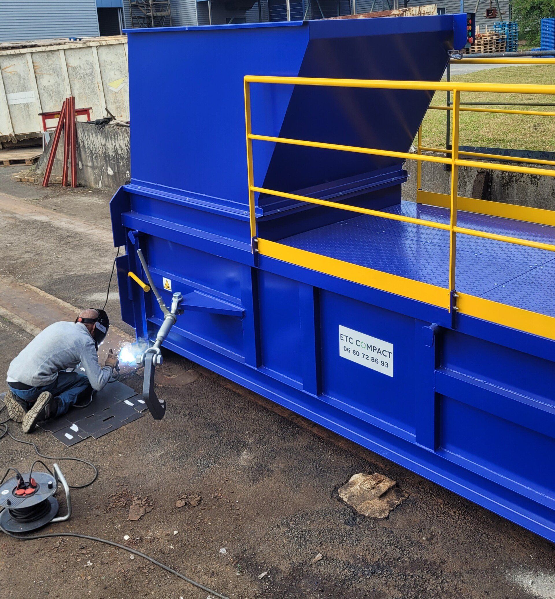 Un technicien ETC Compact effectue la maintenance d'un compacteur de déchets