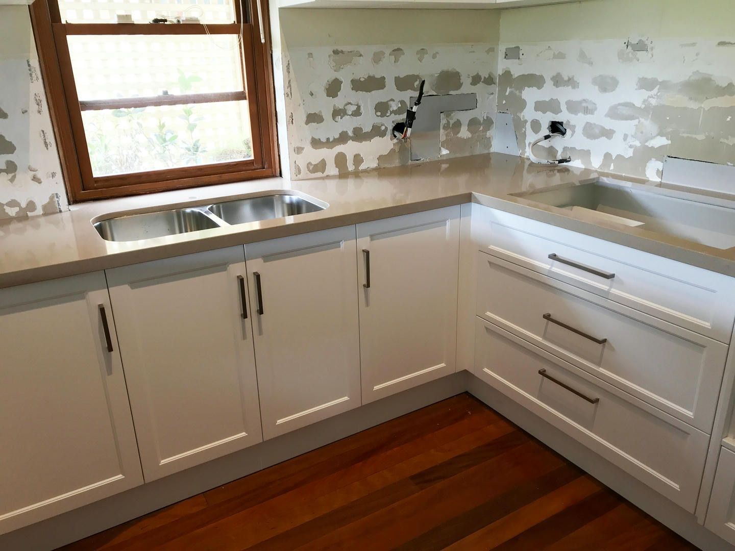 A kitchen with white cabinets and a stainless steel sink