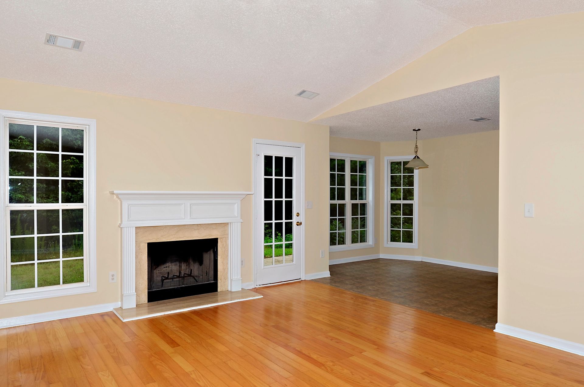 An empty living room with hardwood floors and a fireplace