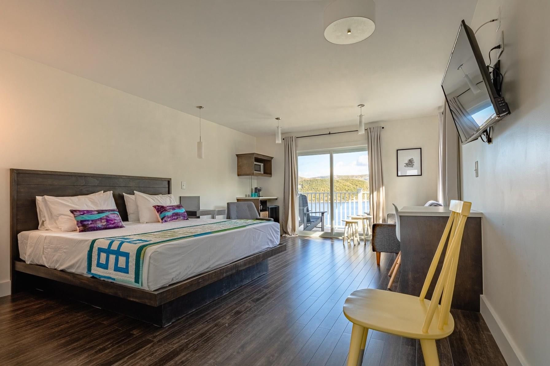A hotel room with a king size bed , a yellow chair , and a flat screen tv.