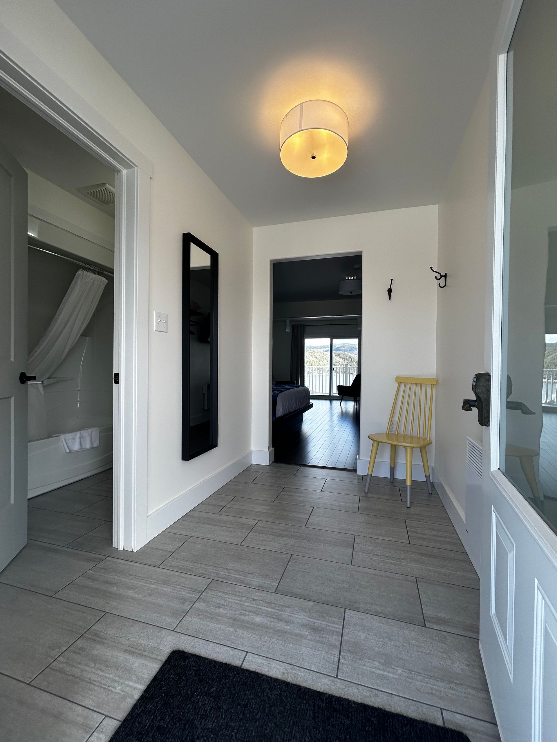 A hallway with a chair and a mirror on the wall