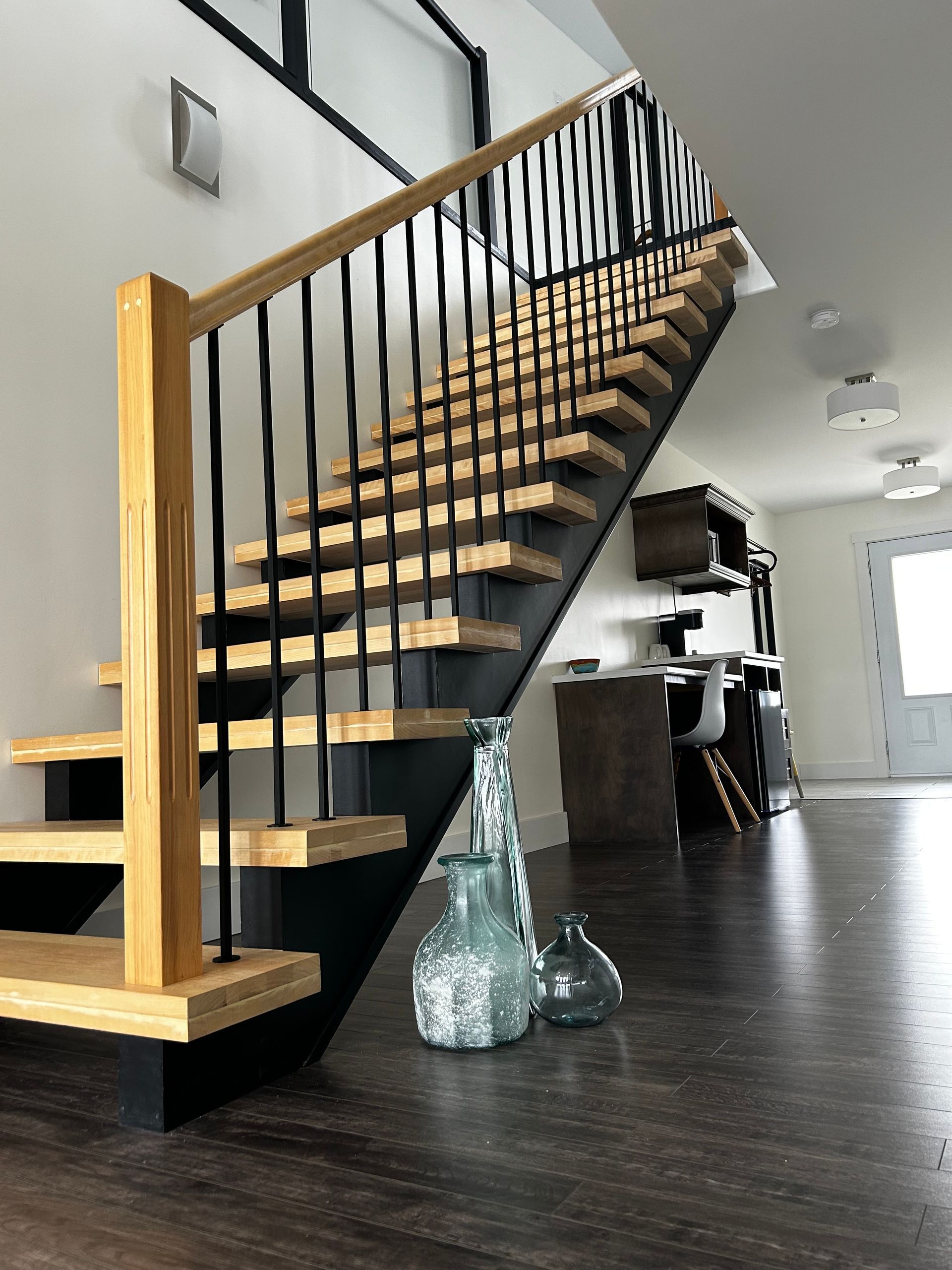 A wooden staircase with a black railing in a living room
