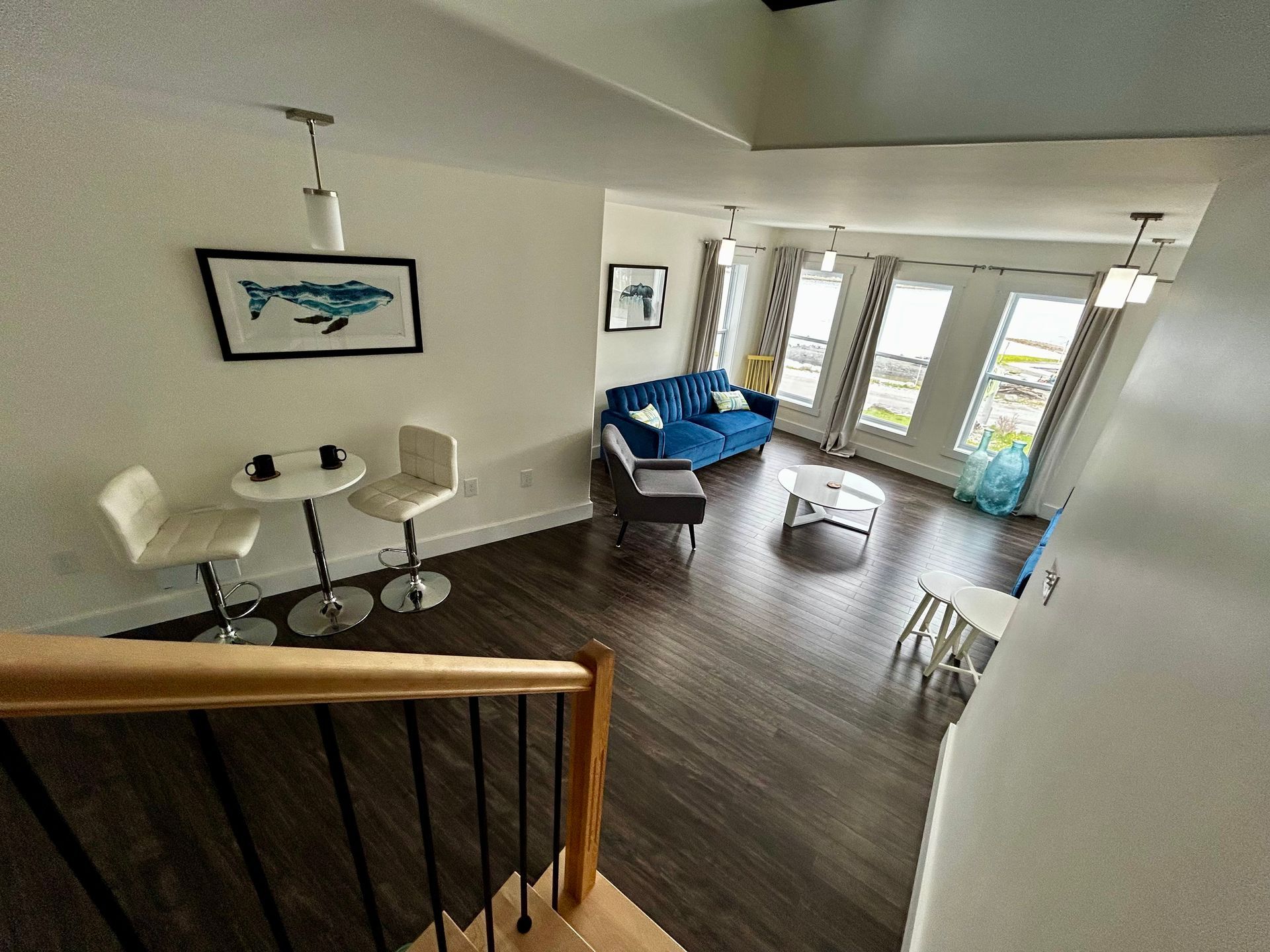 A living room with a blue couch , table , chairs and stairs.