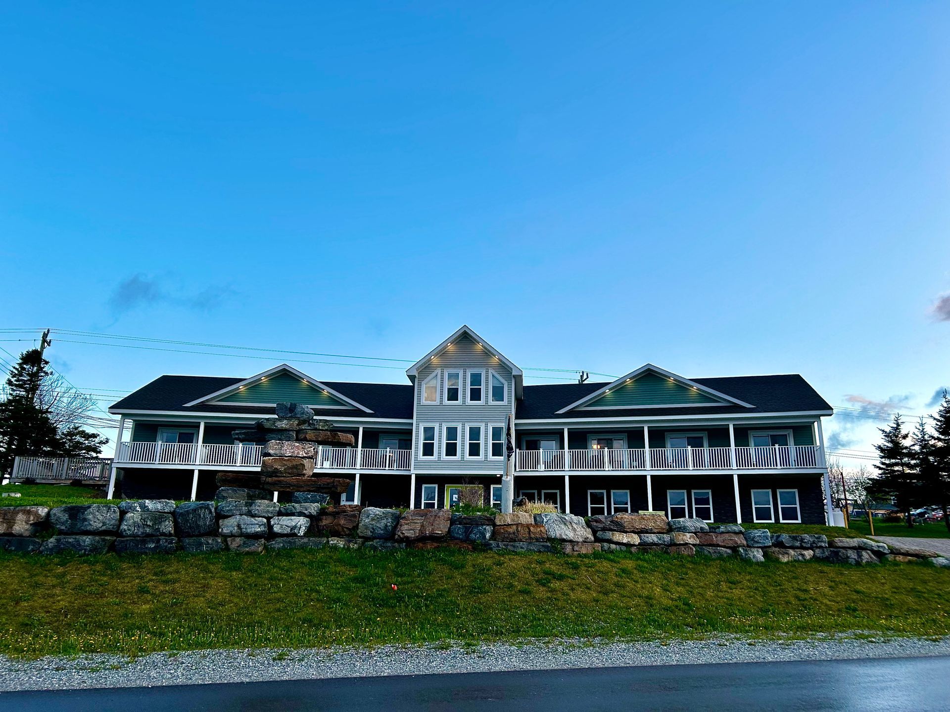A large house with a lot of windows is sitting on top of a grassy hill.