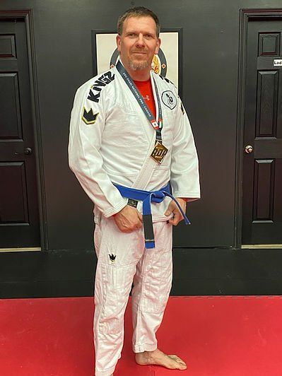 Robbie St. Jean wearing a white Jiu-Jitsu gi and a competition medal