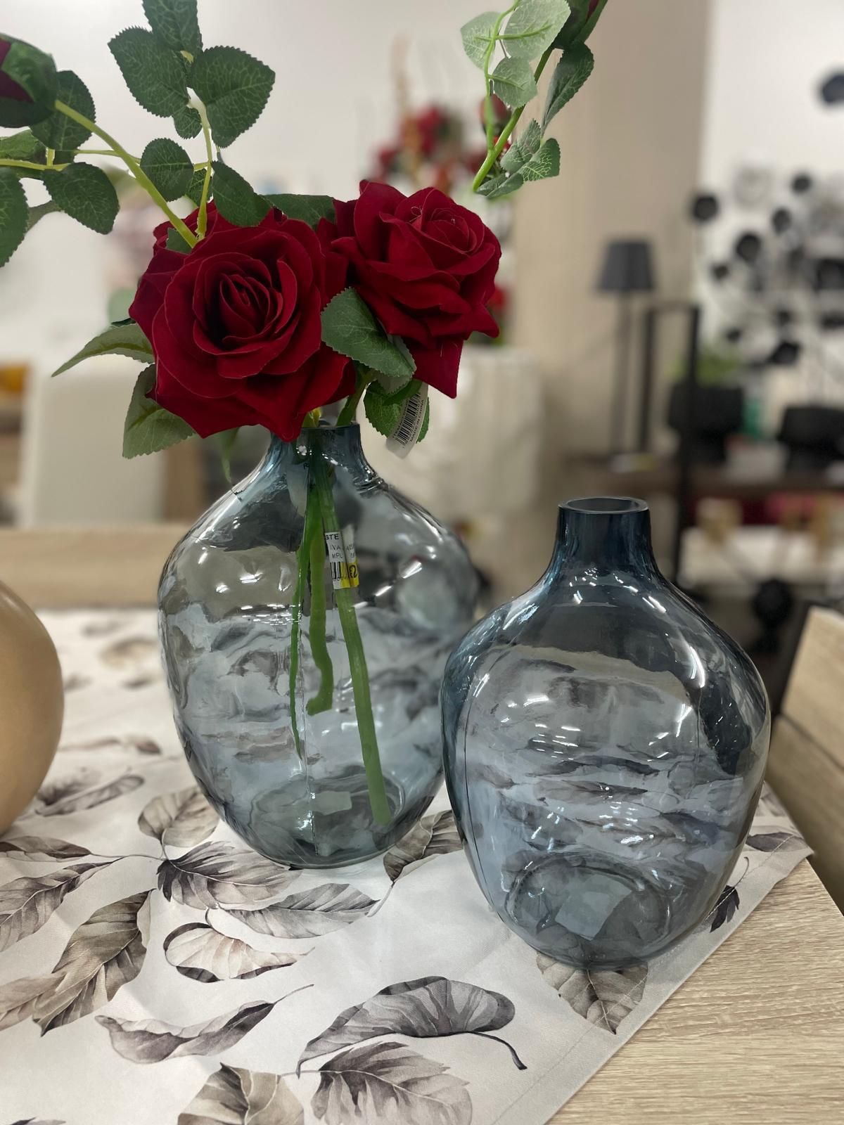 Ci sono due vasi con delle rose rosse su un tavolo.