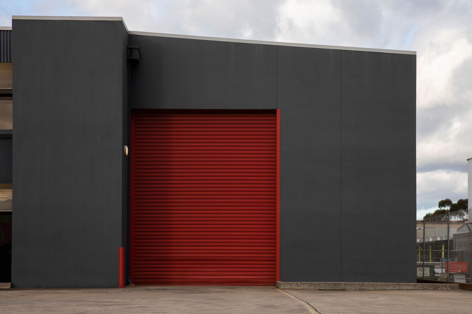 A gray building with a red garage door.