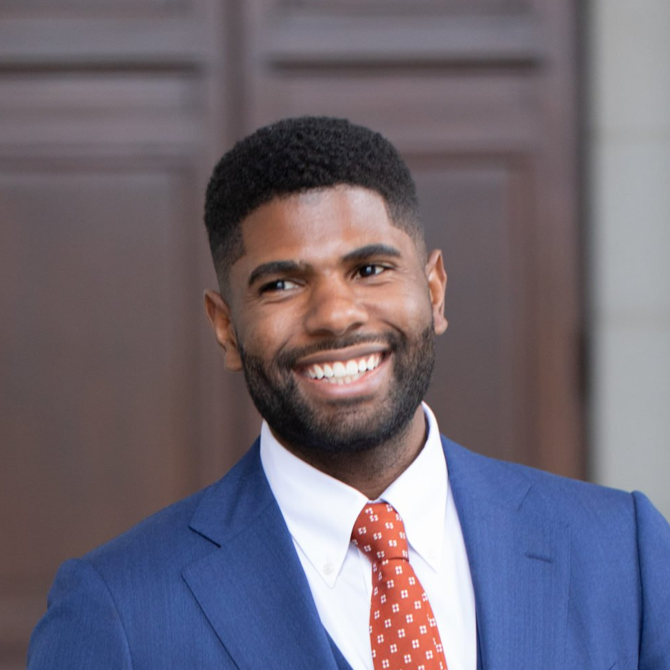 A man in a suit and tie is smiling for the camera