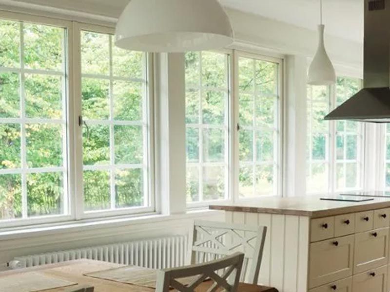 Bright modern kitchen with large windows, white cabinets, and hanging pendant lights
