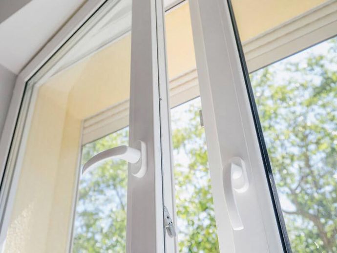 White window frame with an open sliding glass door and a view of trees outside