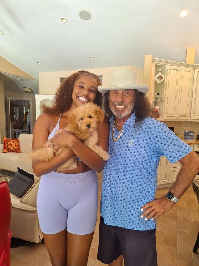 A woman is holding a puppy next to a man in a cowboy hat.