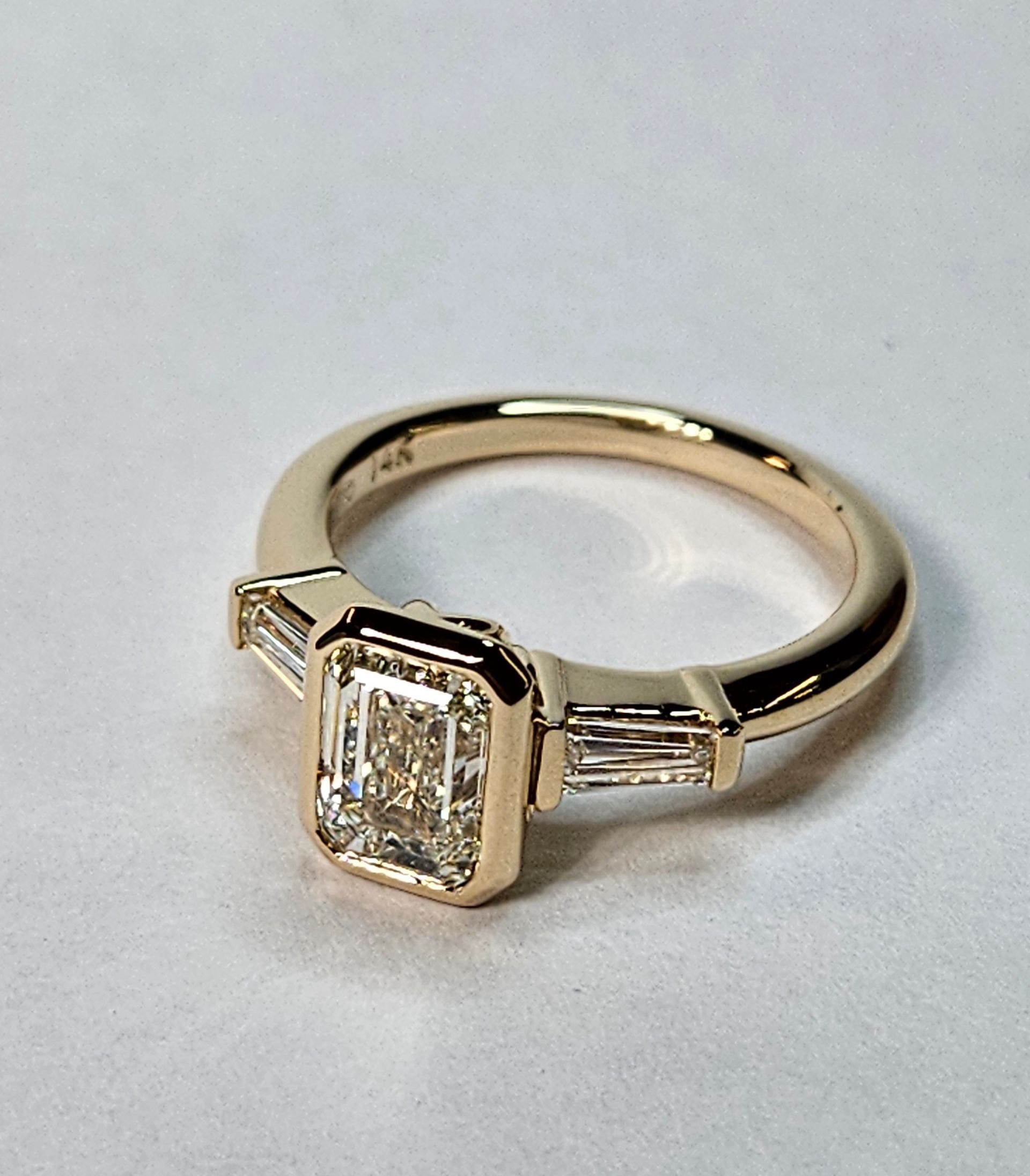 Gold ring with a rectangular diamond centerpiece and side baguette stones on a white background
