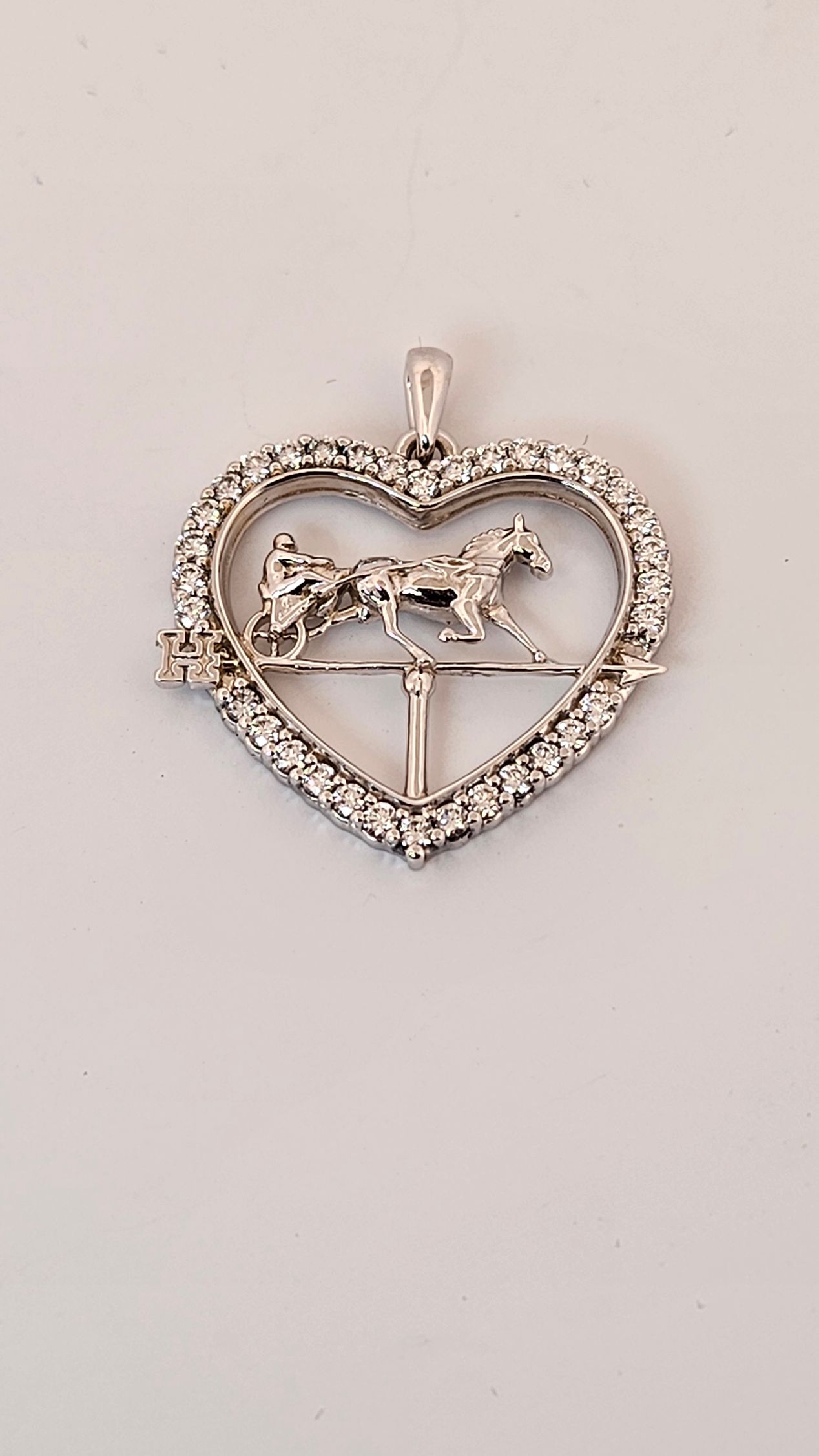 Heart-shaped diamond pendant with a horse silhouette on a light background