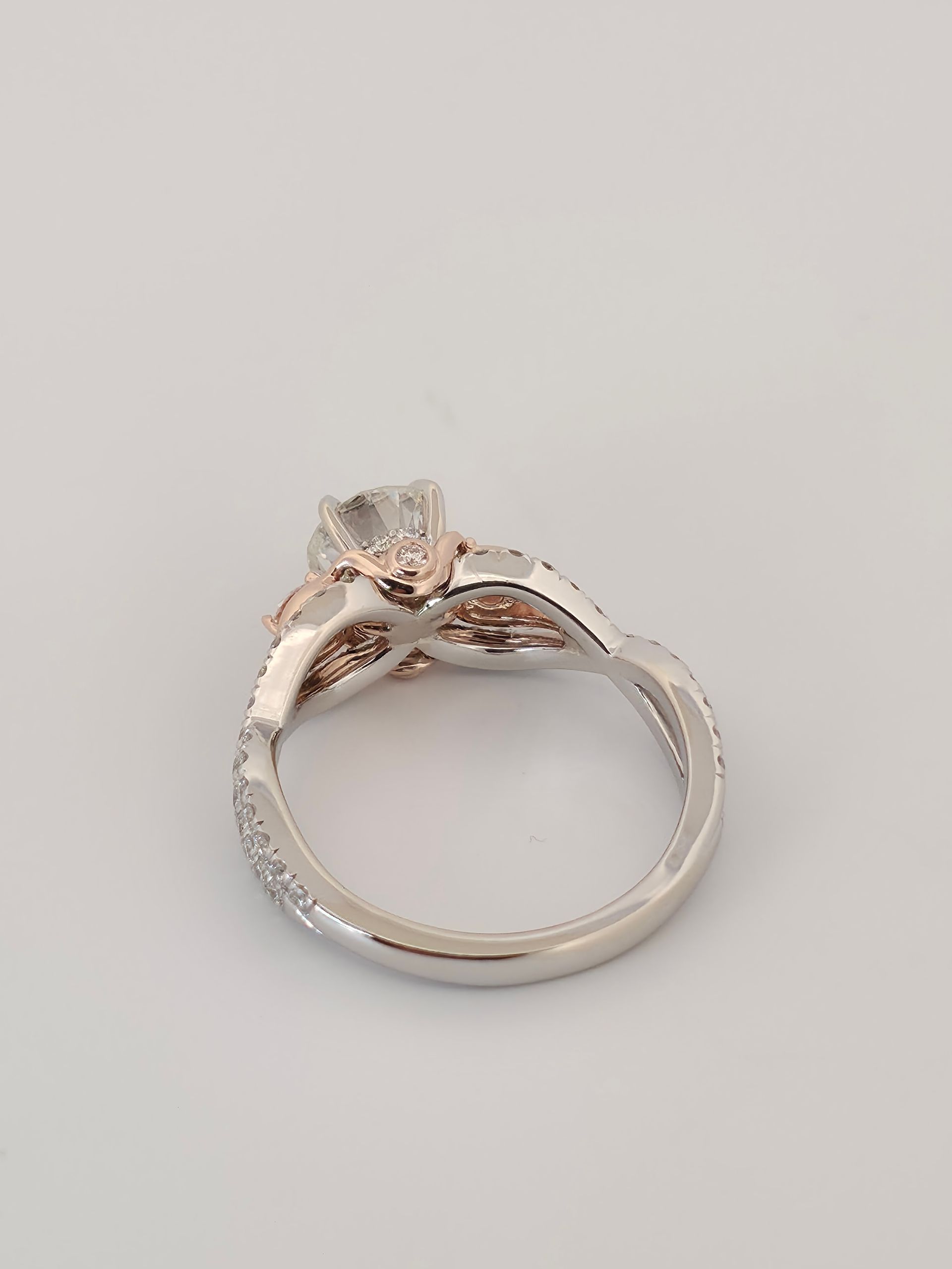 Rose gold ring with a large clear gemstone on a light gray background