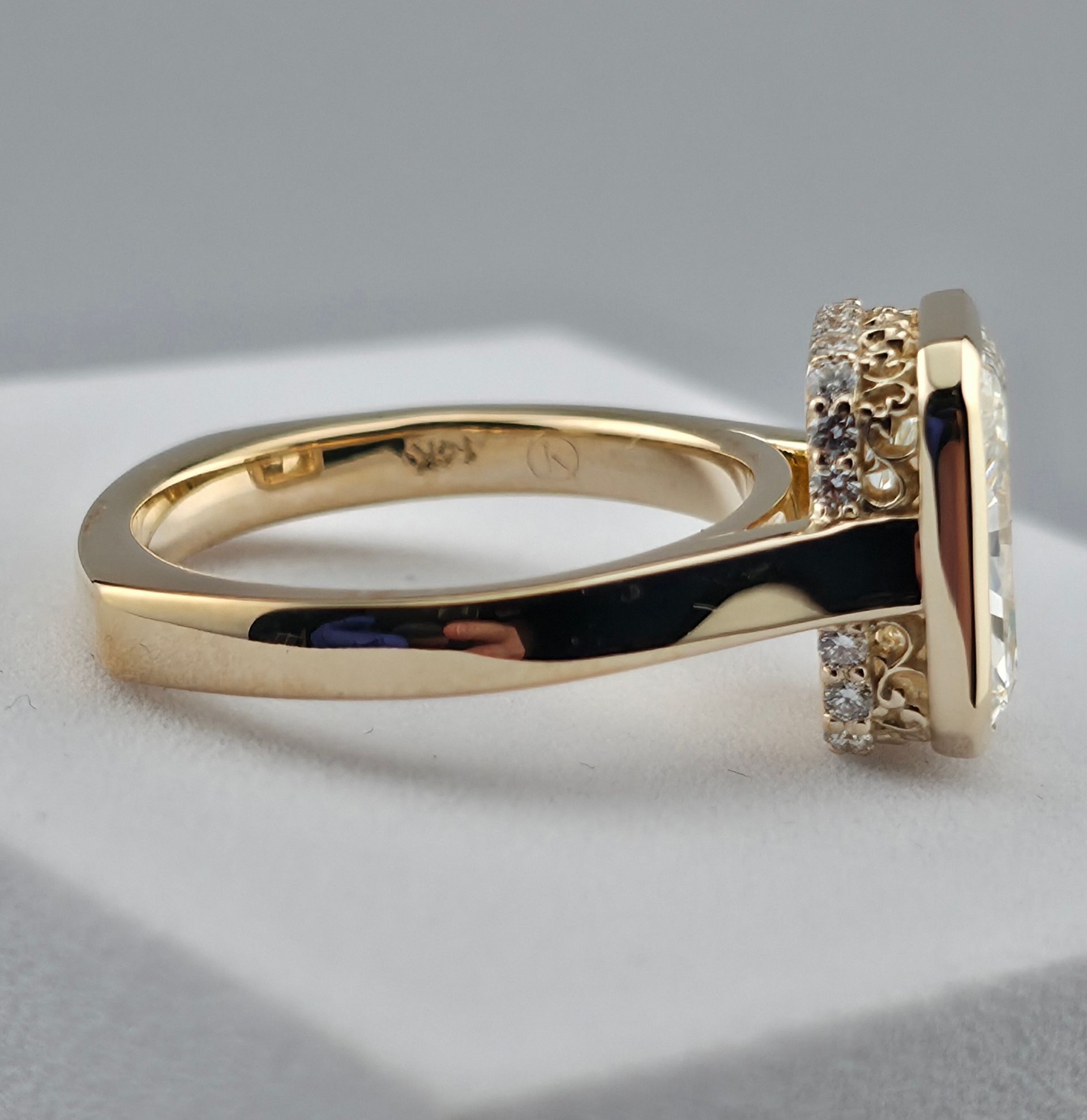 Gold ring with a round diamond setting and small side diamonds on a white surface