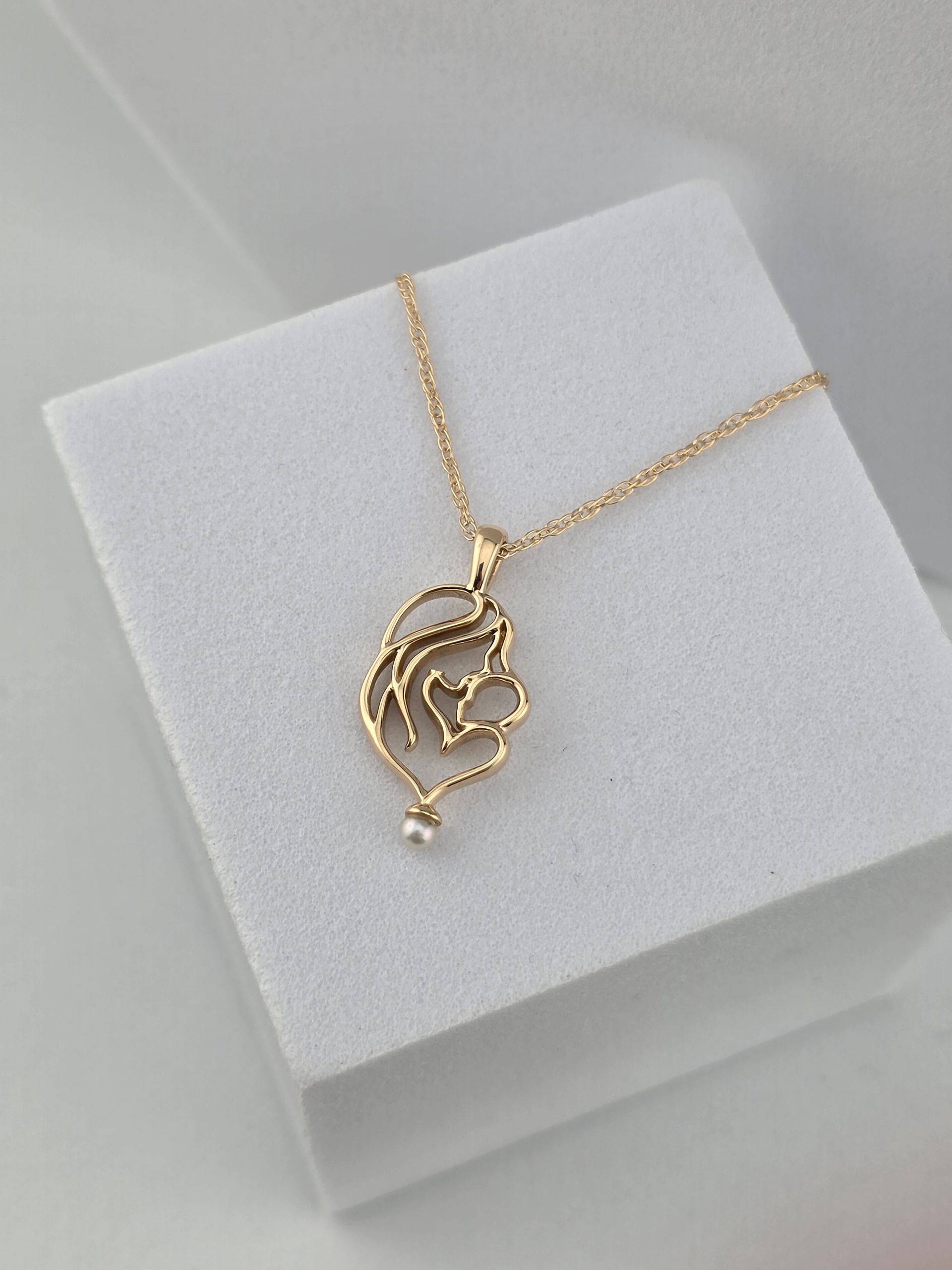 Gold necklace with a heart pendant on a white display box