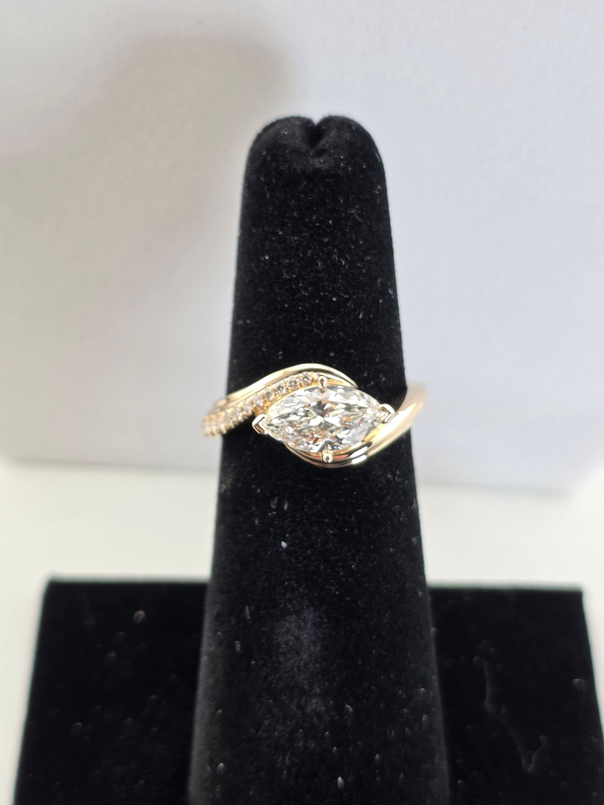 Gold ring with diamonds displayed on a black velvet ring stand