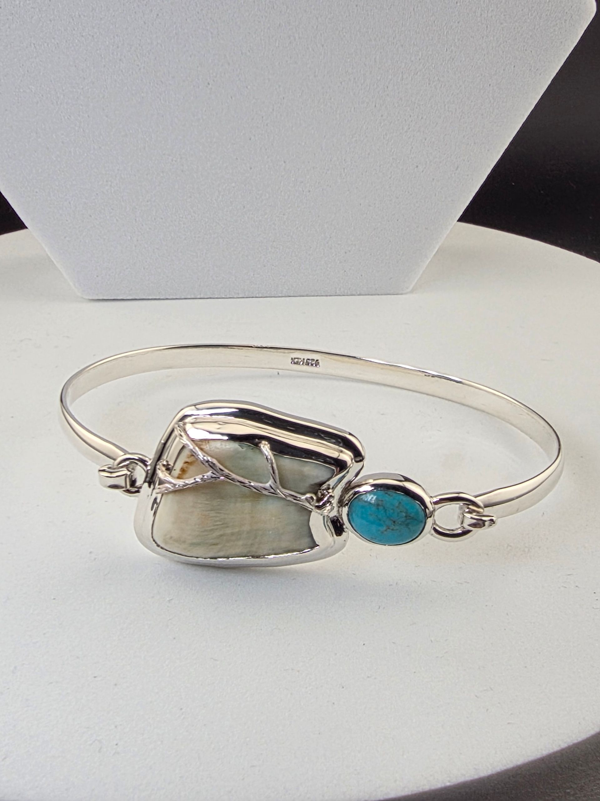 Silver bracelet with a turquoise stone charm on a Elk Ivory.
