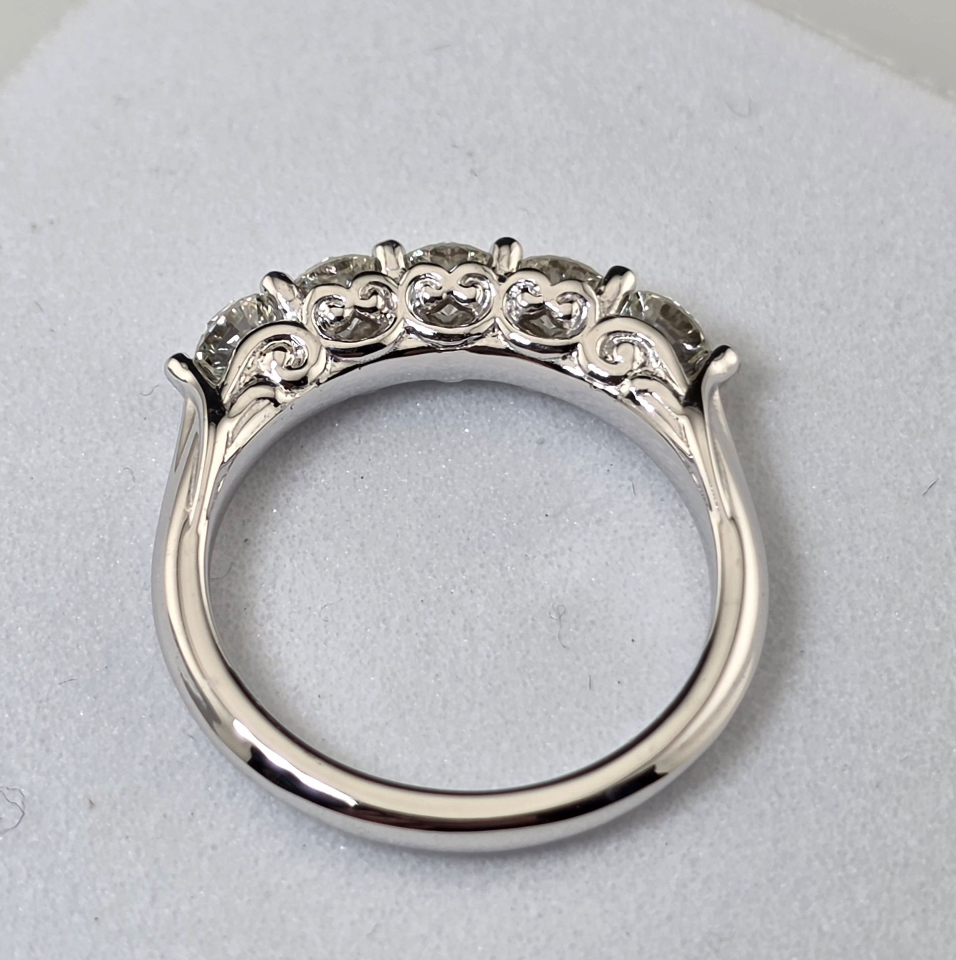 Silver ring with a row of small diamonds on the top, photographed on a light gray background