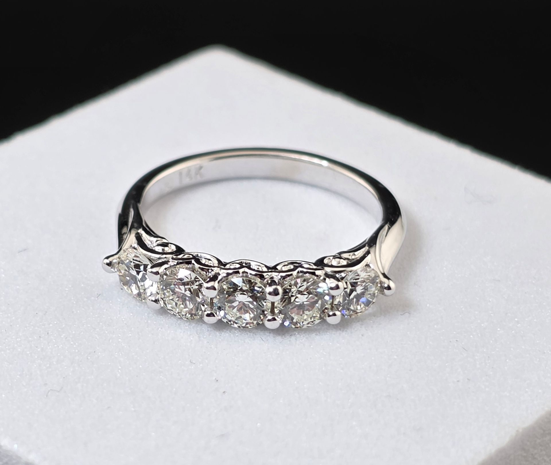Silver ring with a row of diamonds  on a white display surface