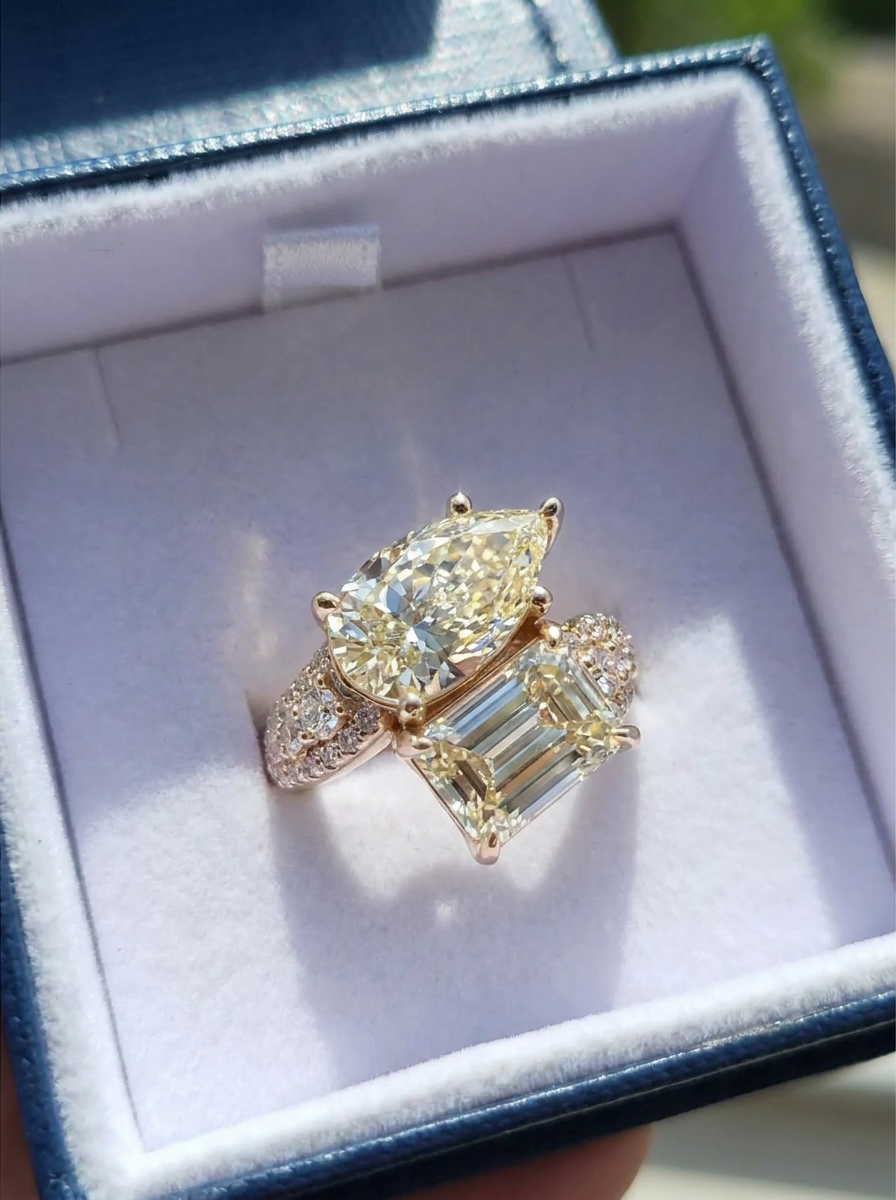 Two Stone gold ring with pave' diamonds set on the sides displayed in a blue velvet jewelry box